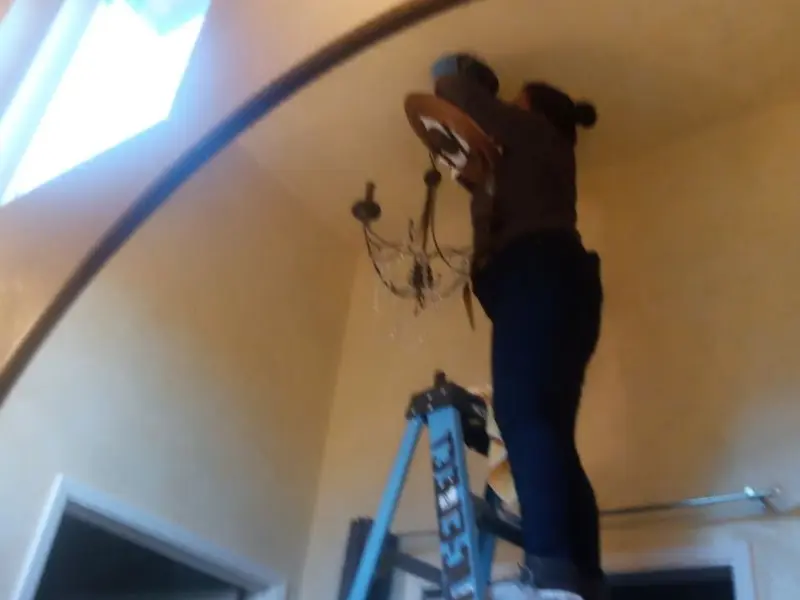 Electrician installing a chandelier in a Vernon residence
